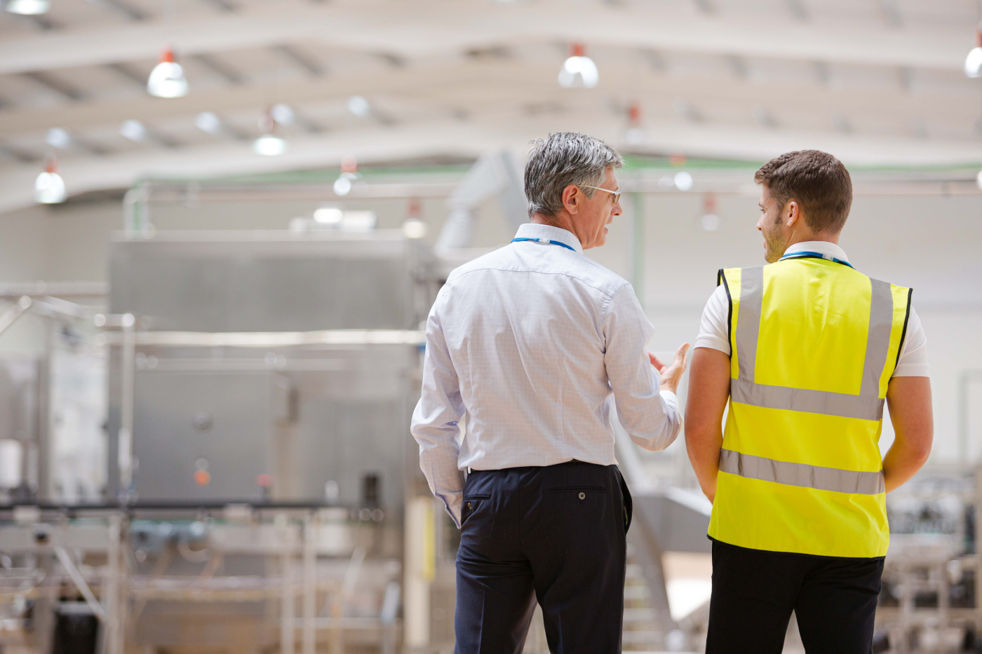 Mann mit Businesskleidung und Mann mit Warnweste für Sicherheit unterhalten sich