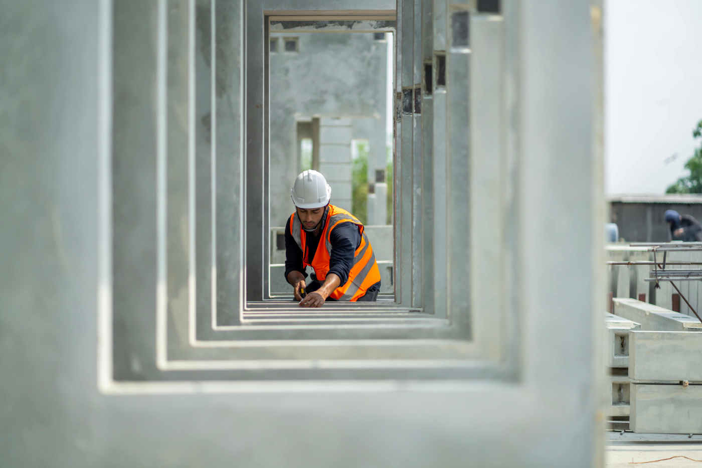 Bauarbeiter im Bauwesen mit Bauhelm und Warnweste beim Bohren an einer Betonfertigteilwand