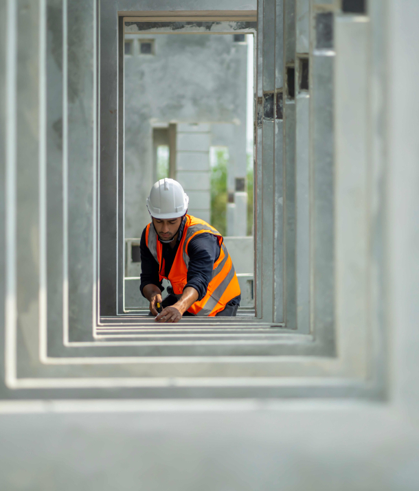 Bauarbeiter im Bauwesen mit Bauhelm und Warnweste beim Bohren an einer Betonfertigteilwand