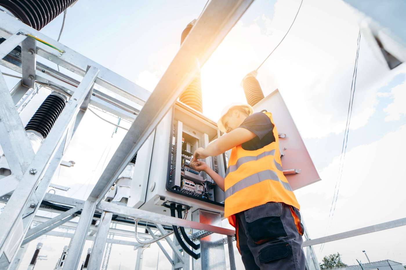 Mann mit Warnweste beim Arbeiten an einem elektronischen Schaltkasten in der Branche Elektrotechnik und Mechatronik