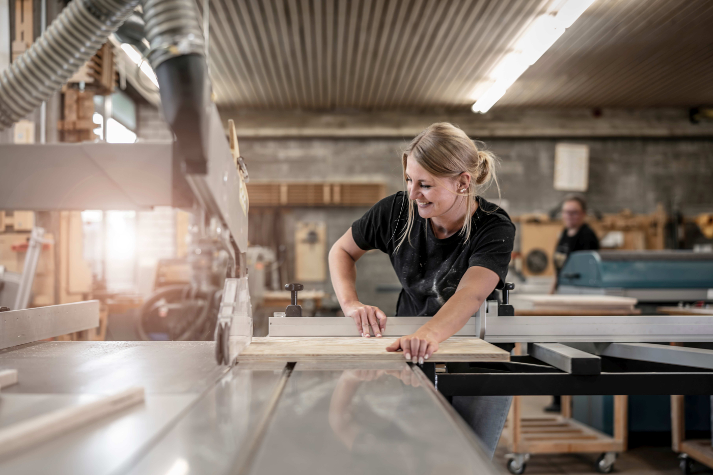 Junge Frau sägt ein Stück Holz an einer Kreissäge zu, Ausbildung Werkmeisterschule