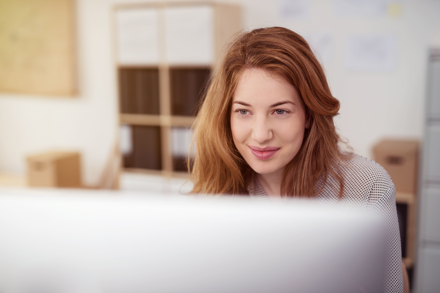 Junge Frau schaut zufrieden in ihren Computerbildschirm